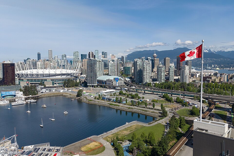 Downtown Vancouver waterfront with a Canadian flag in the foreground.
