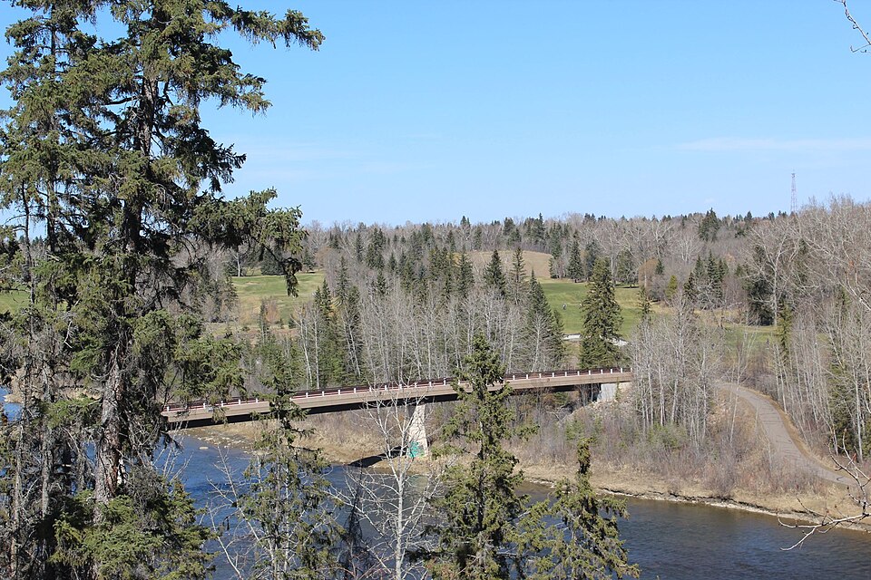 Riverlands Pedestrian Bridge, river and evergreen trees in Red Deer.